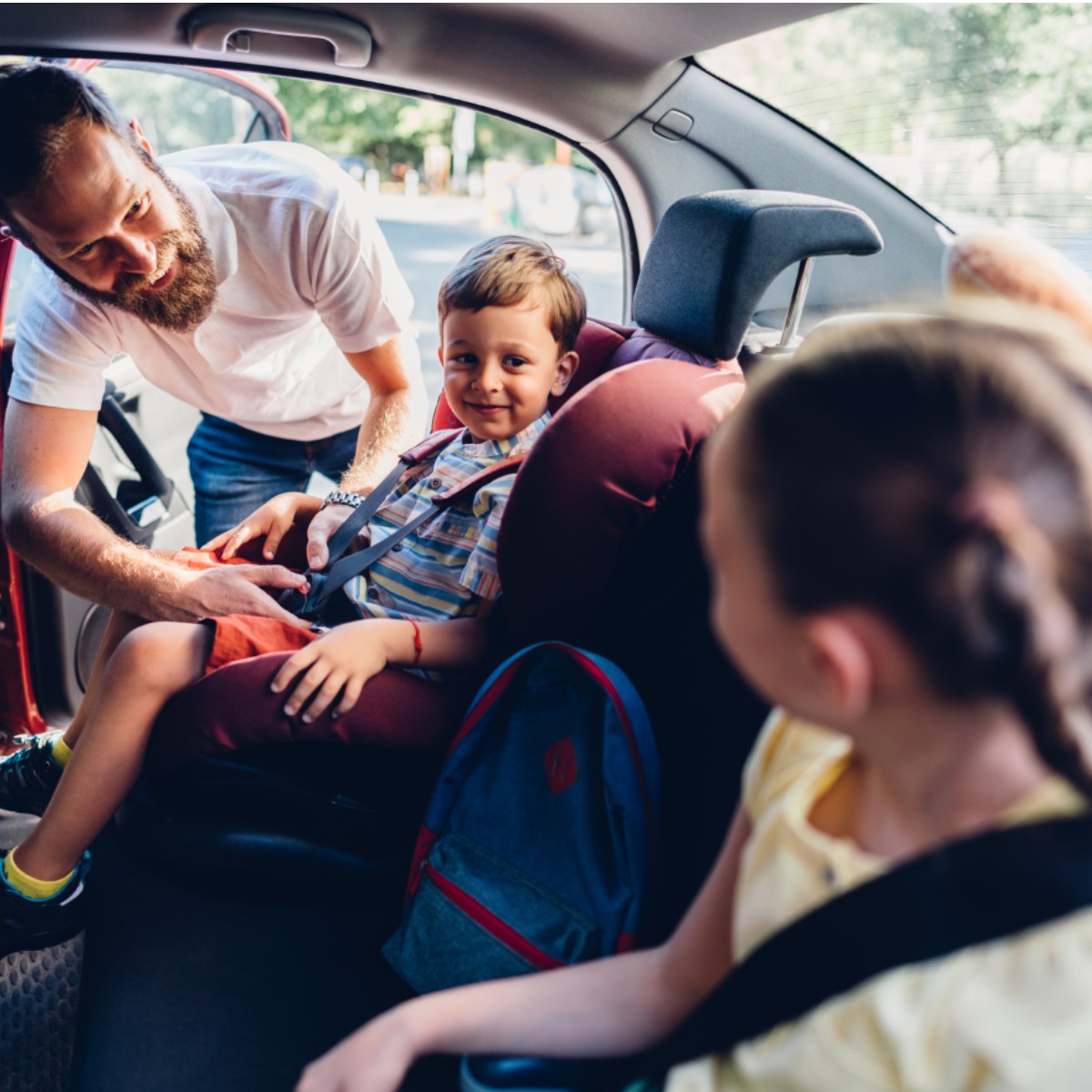 Un parent/guardien aide l’enfant à s’attacher à son siège d’auto